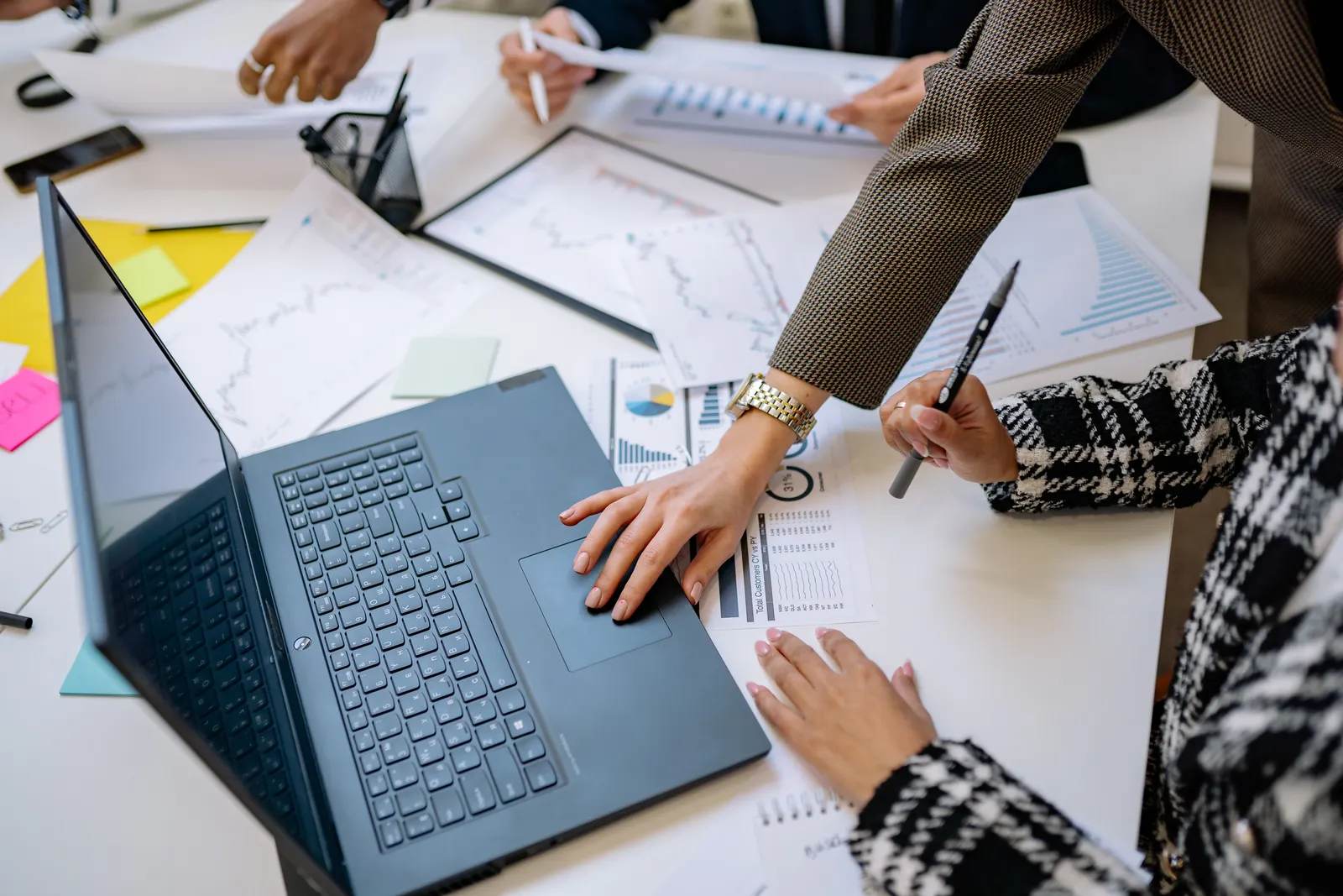 Equipo profesional analizando reportes y gráficas alrededor de una mesa de trabajo